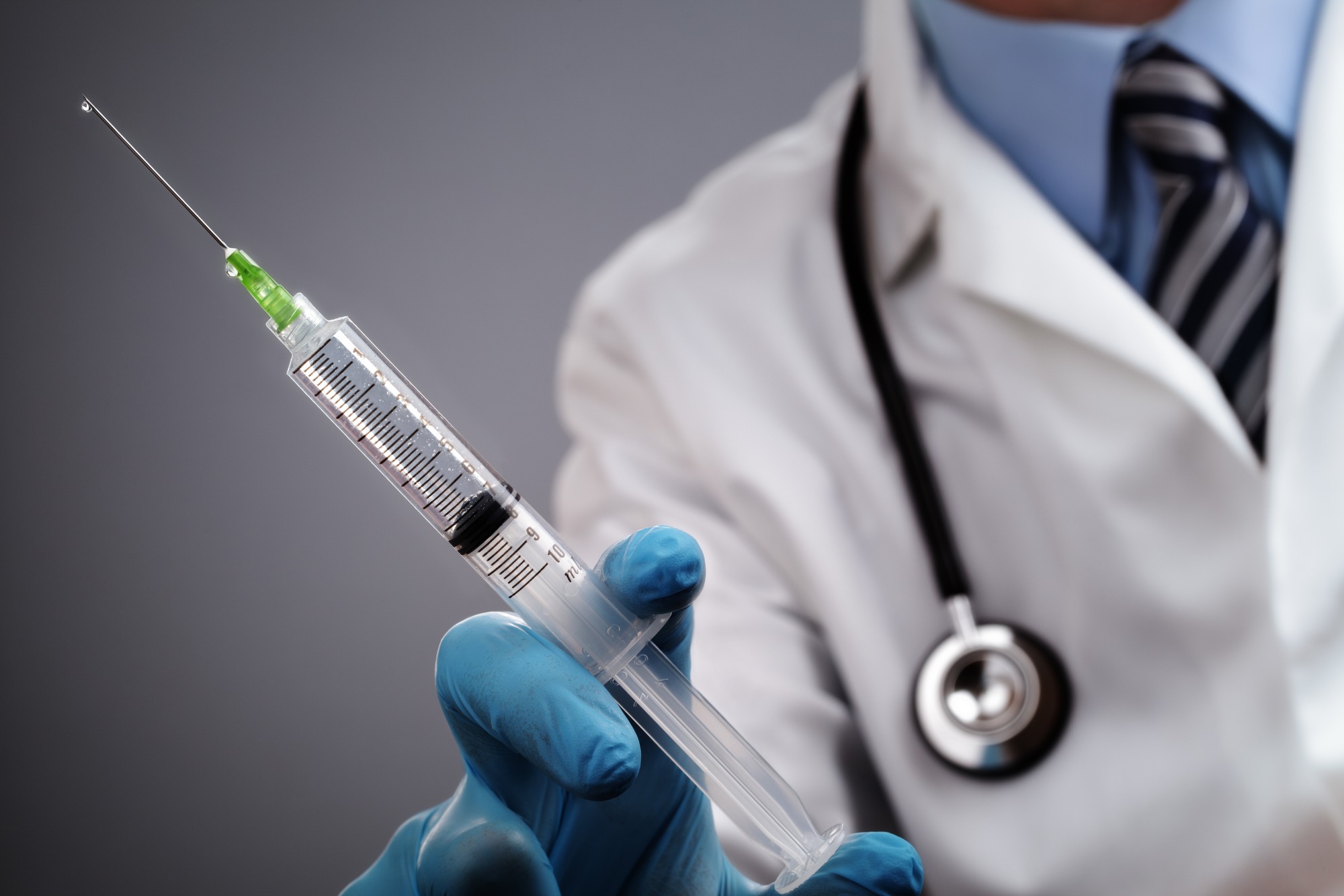 Doctor holding medical injection syringe and stethoscope