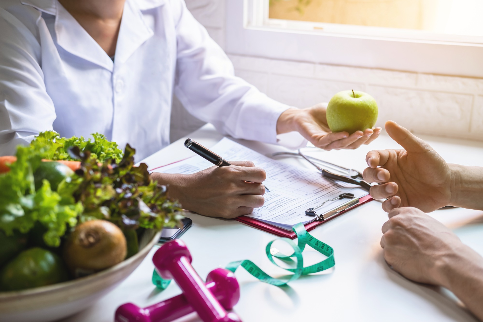 Nutritionist giving consultation to patient with healthy fruit and vegetable