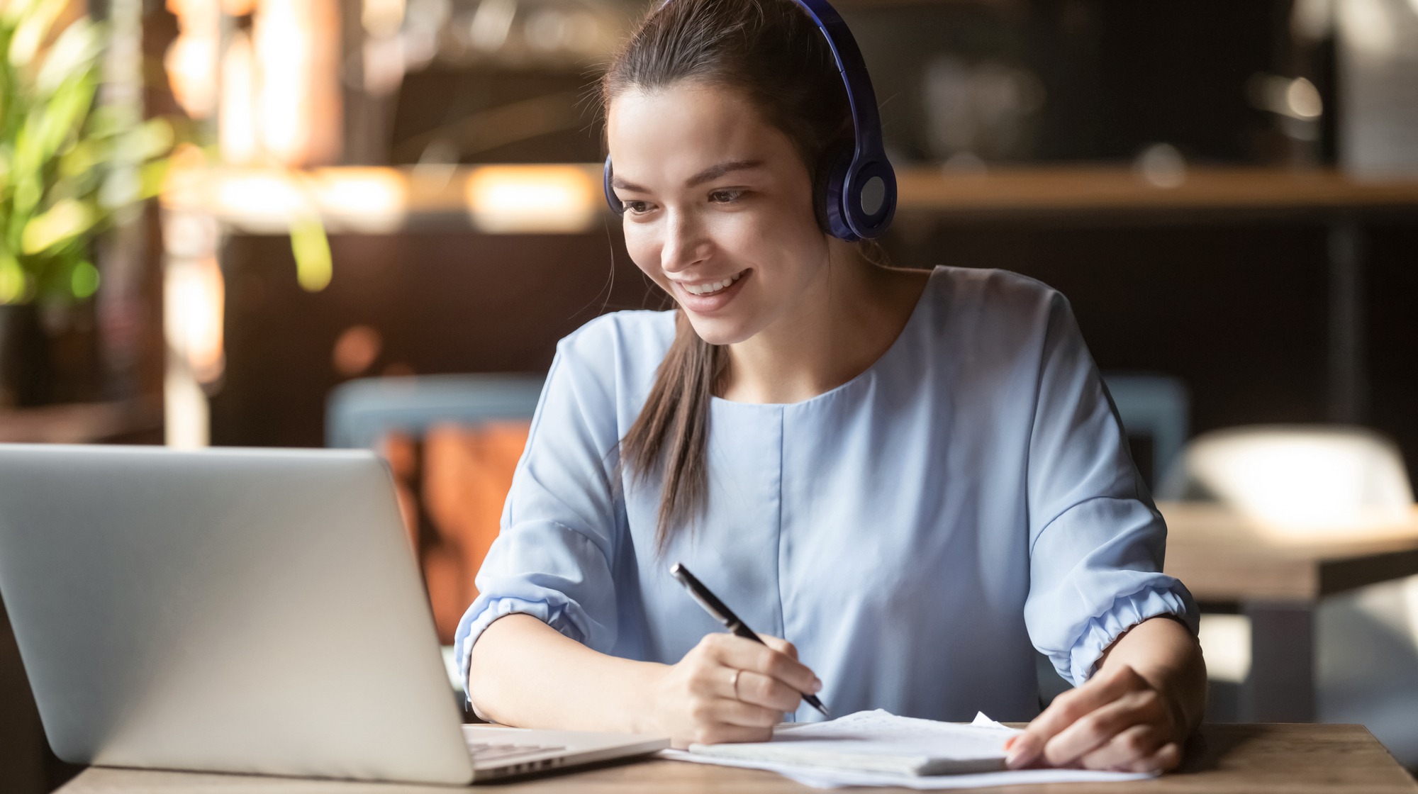 Smiling girl student wear wireless headphone study online with skype teacher