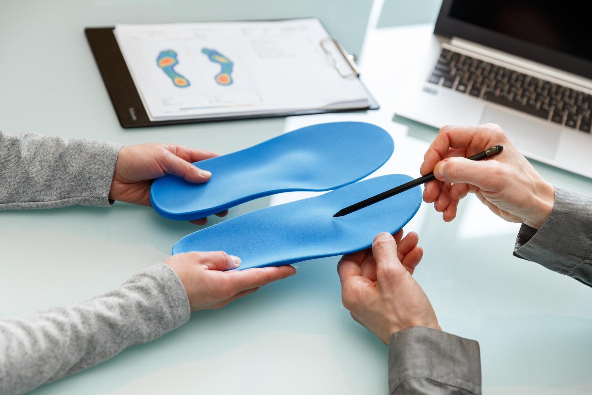 Doctor consulting patient on custom orthotic insoles in a clinic for a personalised custom fit.