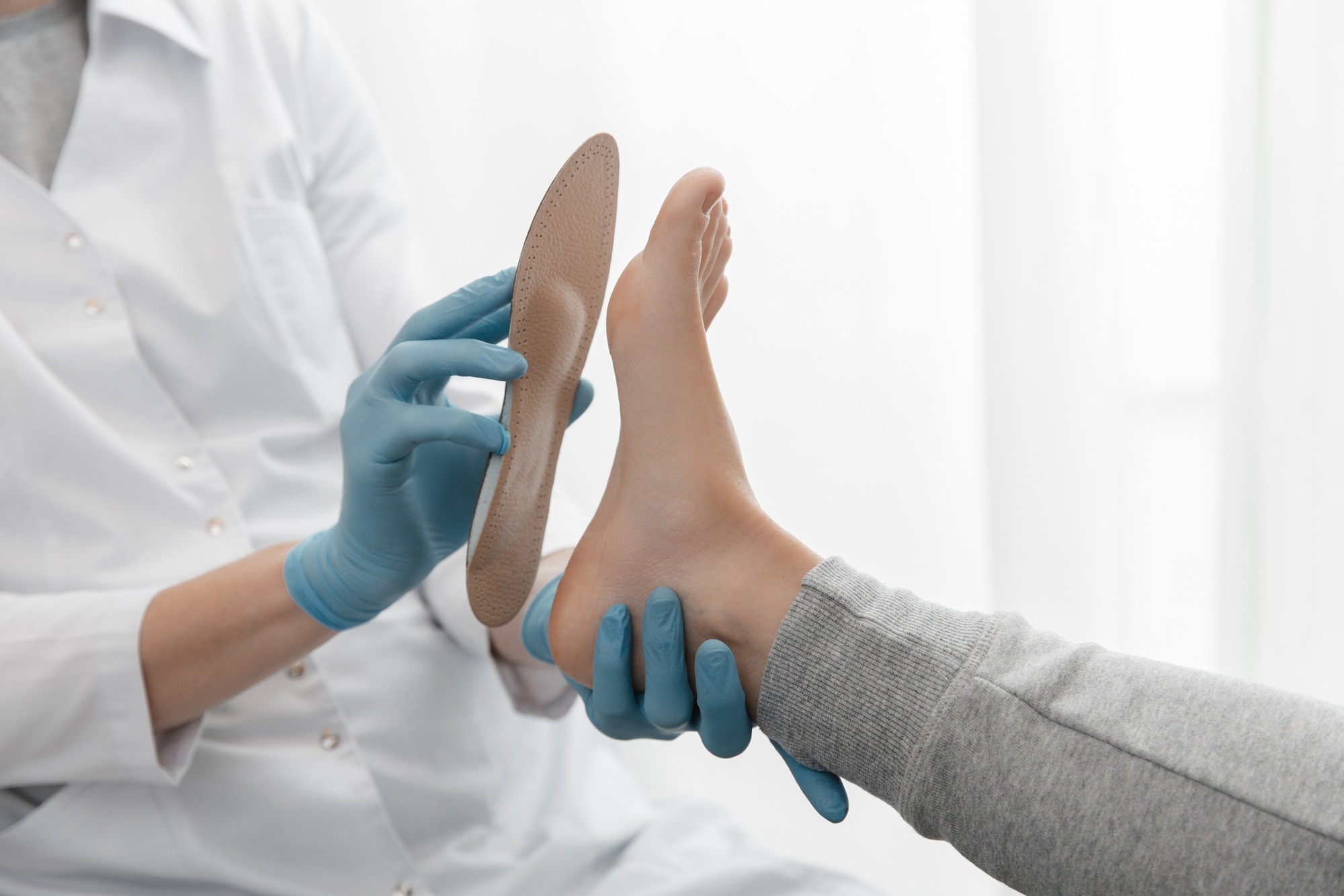 Doctor hands hold an orthopedic insole. Orthopedist tests the medical device.